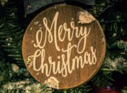 Close-up of a Merry Christmas ornament on a decorated fir tree, evoking festive holiday spirit.